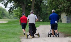 Three golfers push their bags to the next hole of the 2017 Bobcat ND Open