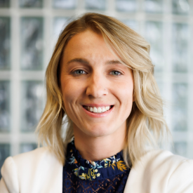 A female therapist with blonde hair wearing a white blazer and a black top